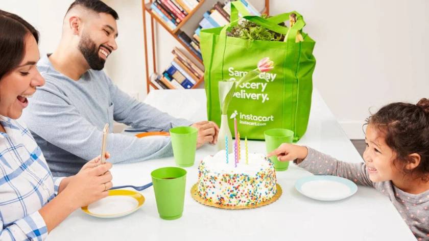 A family is enjoying meal on dinning table having Instacart delivery bag on table